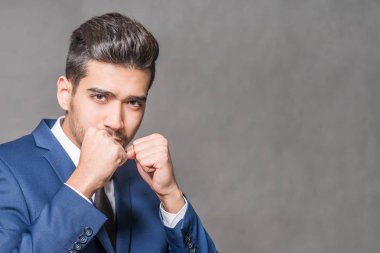 Gri bir arka plan üzerinde mücadele bir duruş ayakta mavi elbiseli Genç çekici adam