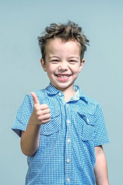 Mavi gömlekli başparmak mavi bir arka plan üzerinde gösterilen boy gülümseyerek