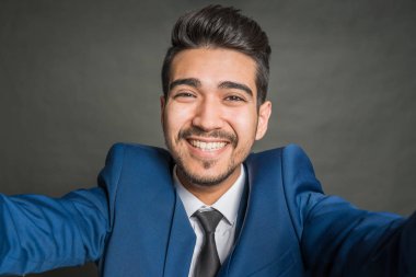 Gri bir arka plan üzerinde mavi elbiseli Genç çekici adam gülümseyen