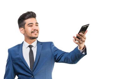 Beyaz bir arka plan üzerinde telefonun ekranına bakarak mavi elbiseli Genç çekici adam. İzole