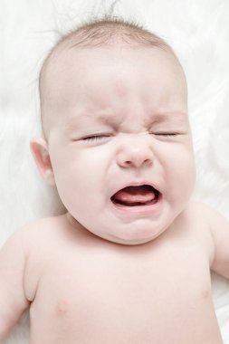 Kabarık beyaz bir arka plan üzerinde Ağlayan bebek yalan