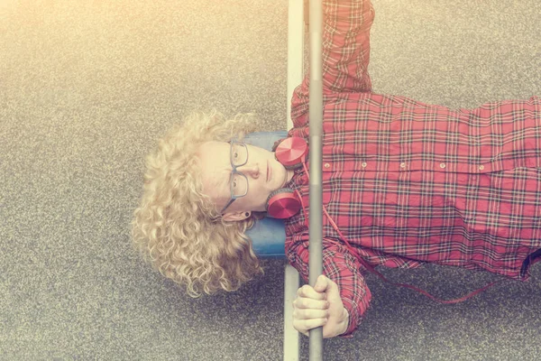 Curly blonde guy in a red shirt lifting the barbell in the sunlight