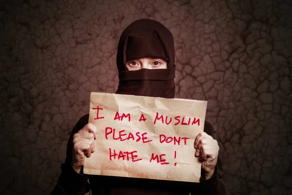 私はイスラム教徒が私を嫌いで茶色の壁にしないでくださいのき裂の碑文とポスターを持って黒のヒジャーブのイスラム教徒の少女 — ストック写真