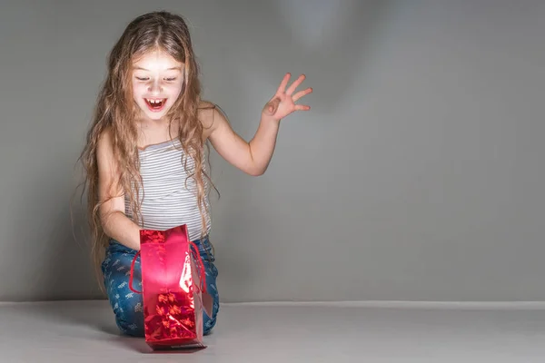 Niña Mira Dentro Una Bolsa Regalo Roja —  Fotos de Stock