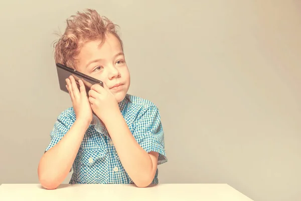 Lindo Niño Hablando Por Teléfono Mientras Está Sentado Mesa Tonificado — Foto de Stock
