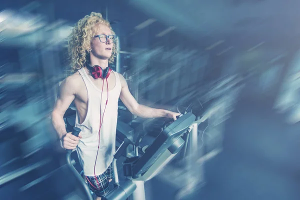 Curly blonde man with glasses trains on a treadmill. Toned