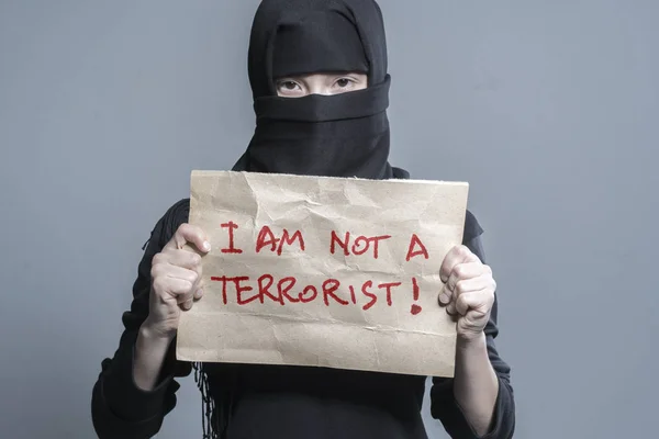 碑文とポスターを持って黒のヒジャーブのイスラム教徒の少女私午前ない テロリスト灰色の背景に — ストック写真