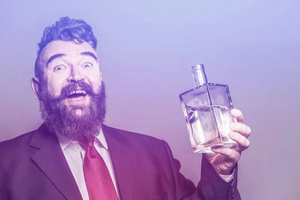 Crazy bearded man in suit holding a bottle of alcohol in his hand on a purple background. Toned