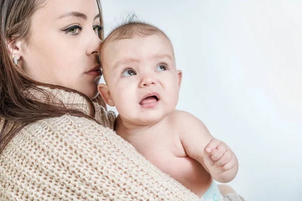 Beyaz bir arka plan üzerinde bir bebek tutan genç kadın