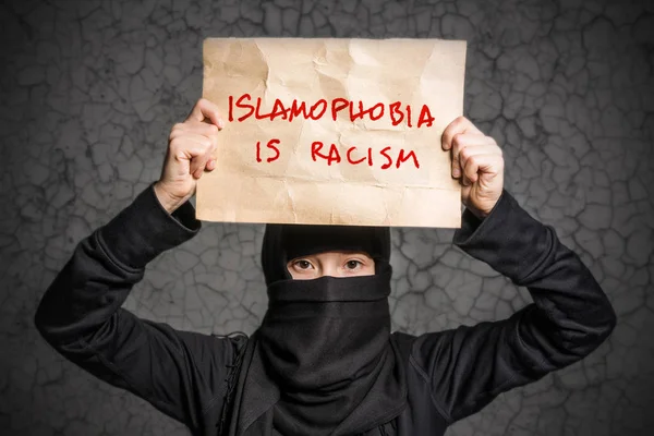 碑文とポスターを持って黒のヒジャーブのイスラム教徒の少女恐怖症は人種差別の壁に亀裂します — ストック写真