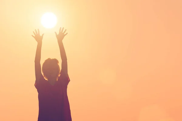 太陽に上げられた手を持つ少女のシルエット — ストック写真