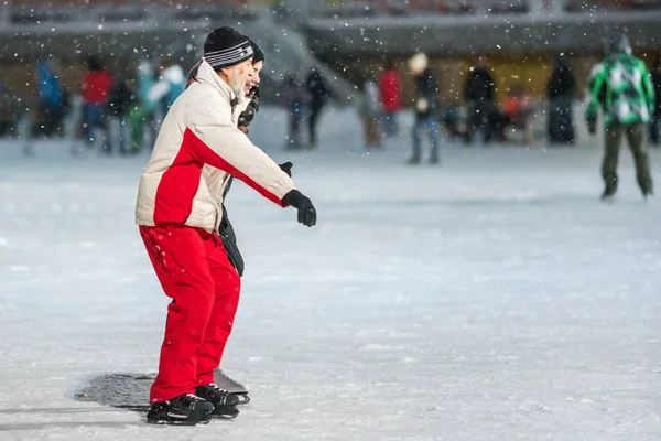 stock image KAZAN, RUSSIA, 22 JANUARY, 2017: Old man and young girl on skating rink in the evening