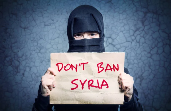 イスラム教徒の少女と青い壁 碑文はありません禁止シリアとポスターを持って黒のヒジャーブの亀裂します — ストック写真
