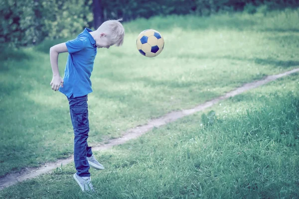 Blond boy beats his head a soccer ball. Toned