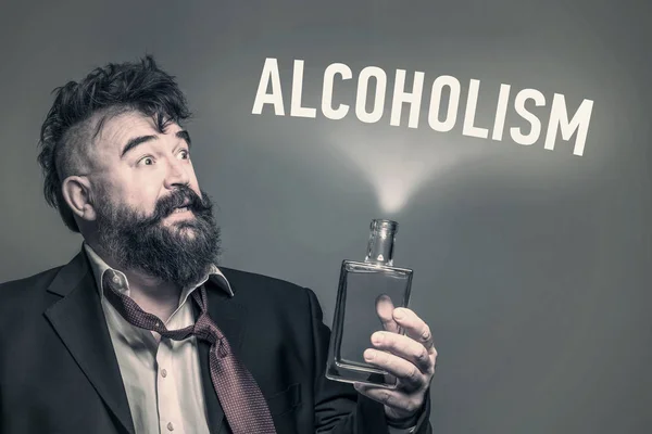 Przestraszony Brodaty Mężczyzna Garnitur Butelką Alkoholu Ręku Obok Napis Alkoholizmu — Zdjęcie stockowe