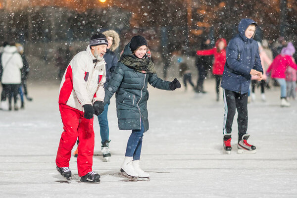 КАЗАН, РОССИЯ, 22 ЯНВАРЯ, 2017: Вечером старик и девушка на катке
