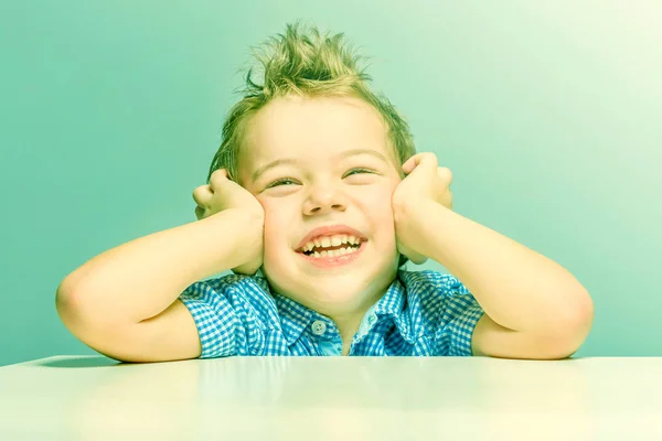 Lindo Chico Sonriente Con Una Camisa Azul Sentado Mesa Tonificado — Foto de Stock