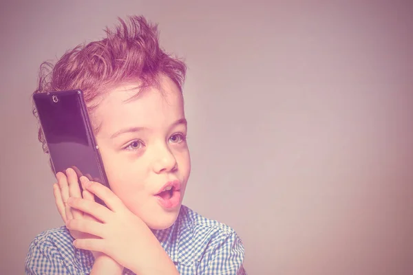 Cute little boy in a blue shirt talking on the phone. Toned
