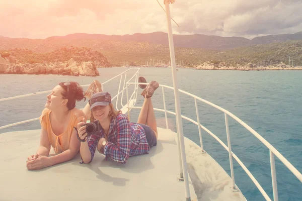 太陽の下でボートの船首の上に横たわるカメラで 人の女性 — ストック写真