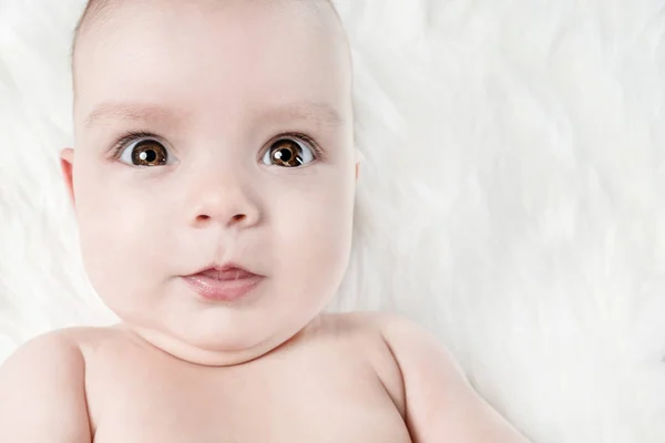 Cute Baby Lies White Fluffy Background Looking Forward — Stock Photo, Image