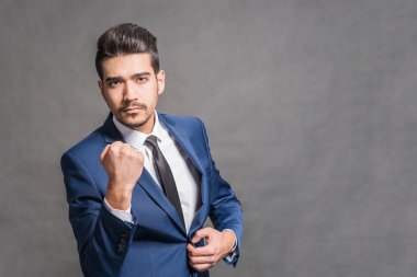 Bir yumruk gri bir arka plan üzerinde gösterilen mavi elbiseli Genç çekici adam