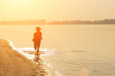 Su üzerinde günbatımında çalışan genç kız