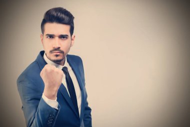 Çekici genç bir yumruk gösterilen mavi takım elbiseli. Tonda