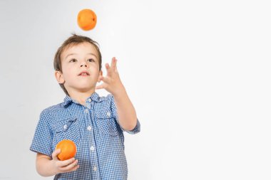 Beyaz zemin üzerine mandalina ile gülümseyen yakışıklı juggles. İzole