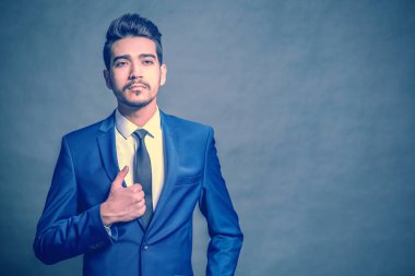 Mavi bir arka plan üzerinde mavi elbiseli Genç çekici adam. Tonda
