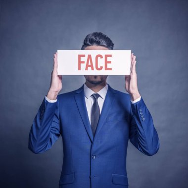 Beyaz bir işareti ile gri bir arka plan üzerinde kırmızı yazıt yüz tutan mavi elbiseli Genç çekici adam. Tonda