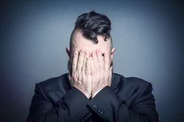 Elbiseli yetişkin sakallı adam yüzünü kapsar