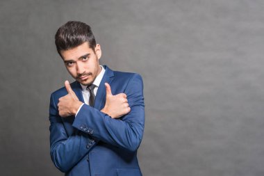 Gri bir arka plan üzerinde bir mavi elbise başparmak genç çekici adam