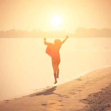 Sarışın genç güneş altında sahilde kadar atlama