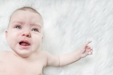 Kabarık beyaz bir arka plan üzerinde Ağlayan bebek yalan