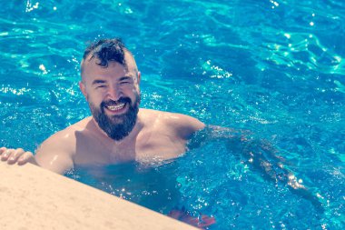 Sakallı adam ile bir su havuzun kenarına yakın bir mohawk saç modeli