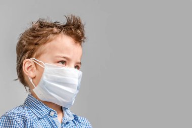 Gri bir arka yüzünde tıbbi maske çocuk. İzole