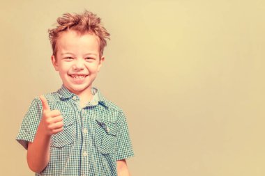 Mavi gömlekli başparmak sarı bir arka plan üzerinde gösterilen boy gülümseyerek