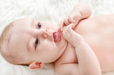 Şirin bebek beyaz kabarık arka plan ve gösteren dil yatıyor