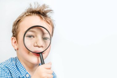 Sevimli çocuk beyaz bir arka plan üzerinde büyüteç üzerinden seyir mavi gömlekli. İzole