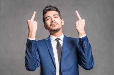 Orta parmak gri bir arka plan üzerinde gösterilen mavi elbiseli Genç çekici adam