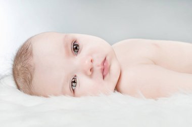 Kabarık beyaz bir arka plan üzerinde şirin bebek yalan