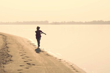 Günbatımında sörf hat boyunca çalışan mutlu sarışın kız Genç
