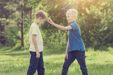 Sarışın çocuk parmağını onun arkadaşı parkta alnına'ı tıklatın. Tonda