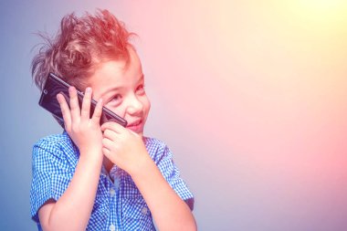 Sevimli küçük çocuk güneş ışığı altında telefonda konuşuyor