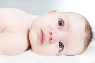 Kabarık beyaz bir arka plan üzerinde şirin bebek yalan