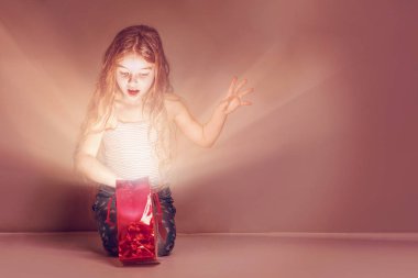 Bir parıltı ile kırmızı bir çanta içinde sürpriz kız görünüyor