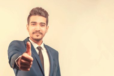 Başparmak gösterilmesini mavi elbiseli Genç çekici adam. Tonda