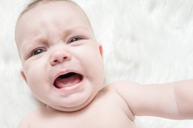 Kabarık beyaz bir arka plan üzerinde Ağlayan bebek yalan