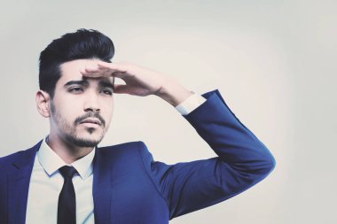 Mavi elbiseli Genç çekici adam uzakta gözlerini elini tutarak görünüyor. Tonda