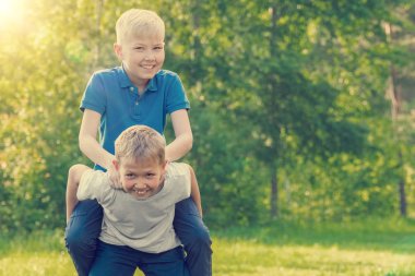 Sarışın çocuk bir arkadaş bir güneşli yaz parkta arkasında sürme